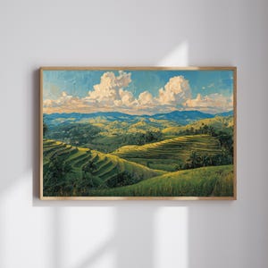 Puede incluir: Una pintura de paisaje enmarcada representa una exuberante ladera aterrazada bajo un cielo azul brillante salpicado de nubes blancas y esponjosas. La obra de arte presenta verdes, azules y amarillos vibrantes, capturando una escena natural serena. Las palmeras y las colinas onduladas añaden profundidad.