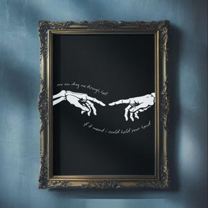 Könnte beinhalten: Ein rechteckiger Wandkunstdruck in einem verzierten dunkelgoldenen Rahmen mit schwarzem Hintergrund und zwei weißen Skeletthänden, die aufeinander zu greifen. Der Text lautet: you can drag me through hell if it meant i could hold your hand.
