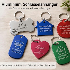 Könnte beinhalten: Sechs Aluminium-Schlüsselanhänger in verschiedenen Formen wie Knochen, Haus, Kreis, Herz und zwei Rechtecke. Die Anhänger sind mit individuellen Gravuren versehen, darunter Namen, Adressen, Telefonnummern, Logos sowie Pfoten-, Auto- und Pflanzensymbole.