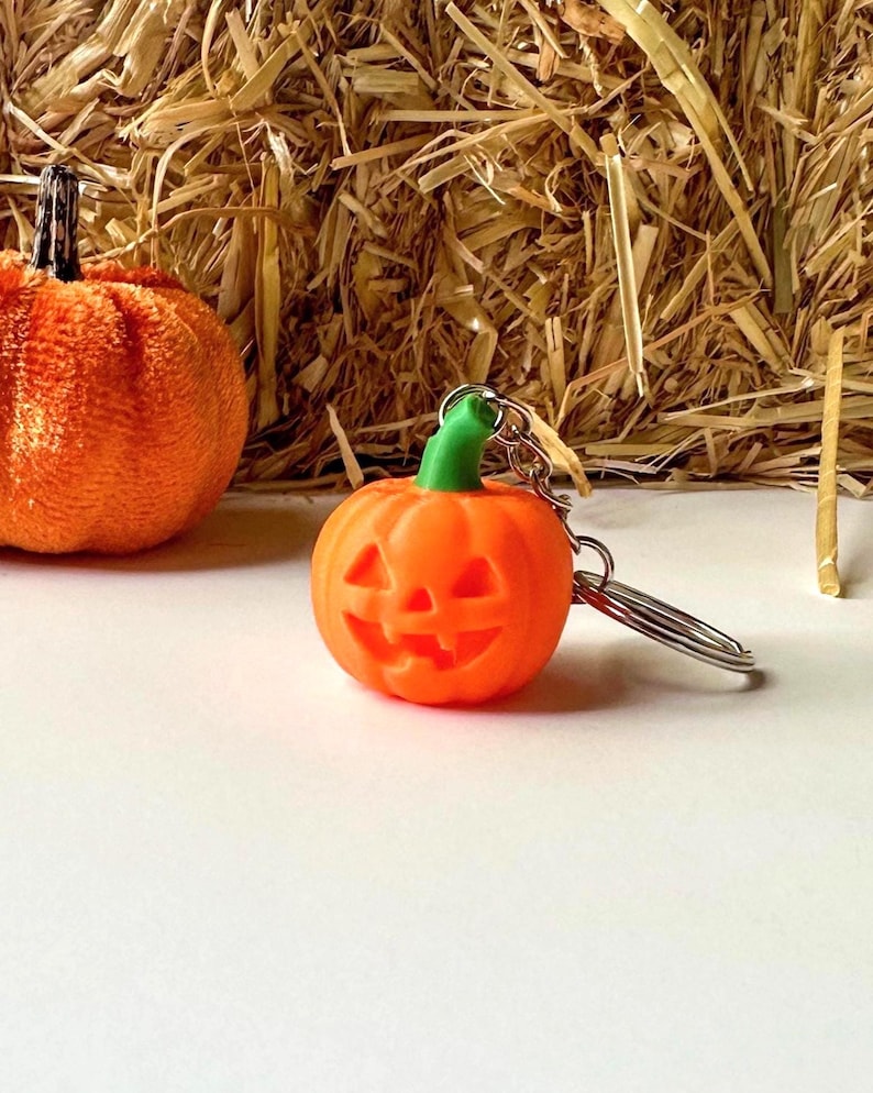 Pumpkin Halloween keychain with green stem displayed on white background with small pumpkin decor.