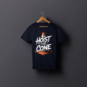 May include: Dark navy blue t-shirt featuring the text "Hoist the Cone" in white, with an orange traffic cone graphic. The tee shirt is displayed on a wooden hanger against a dark grey backdrop.