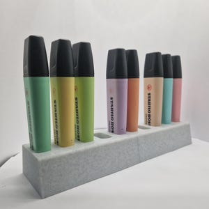 Peut inclure: Ensemble de surligneurs STABILO BOSS colorés dans un support gris. Les surligneurs sont de différentes couleurs, dont le vert, le jaune, l'orange, le rose et le bleu. Le texte "STABILO BOSS" est imprimé sur le côté de chaque surligneur.