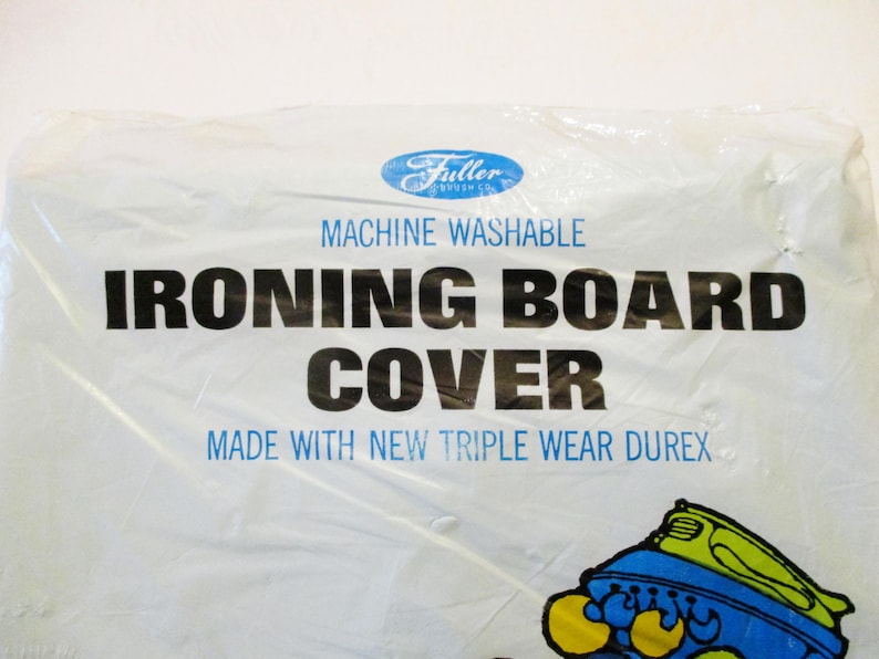 Pode incluir: Capa de t&aacute;bua de engomar branca em embalagem de pl&aacute;stico. A capa tem o texto "MACHINE WASHABLE IRONING BOARD COVER" em preto e azul. O logotipo da Fuller Brush Co. est&aacute; no topo.