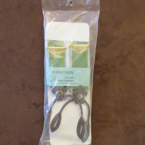 May include: A package containing Marathon brand adjustable wader suspenders. The suspenders have green and blue striped straps with gold-colored accents. The suspenders have dark brown leather-like attachments and are packaged in a clear plastic bag.