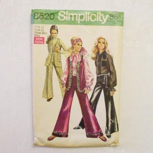 May include: Vintage Simplicity sewing pattern featuring three women's outfits. The pattern includes a green and gold suit, a pink ensemble with a vest, and a black outfit with flared pants. The pattern is labeled "8520" and "Simplicity".