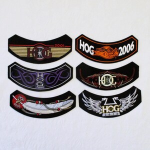 May include: Six black curved embroidered patches featuring HOG text and various designs including a 2001 striped logo, a 2006 orange hog head, a 2004 purple tribal pattern, a 2009 pinstripe design, a 2005 feather graphic, and a 2016 winged emblem.
