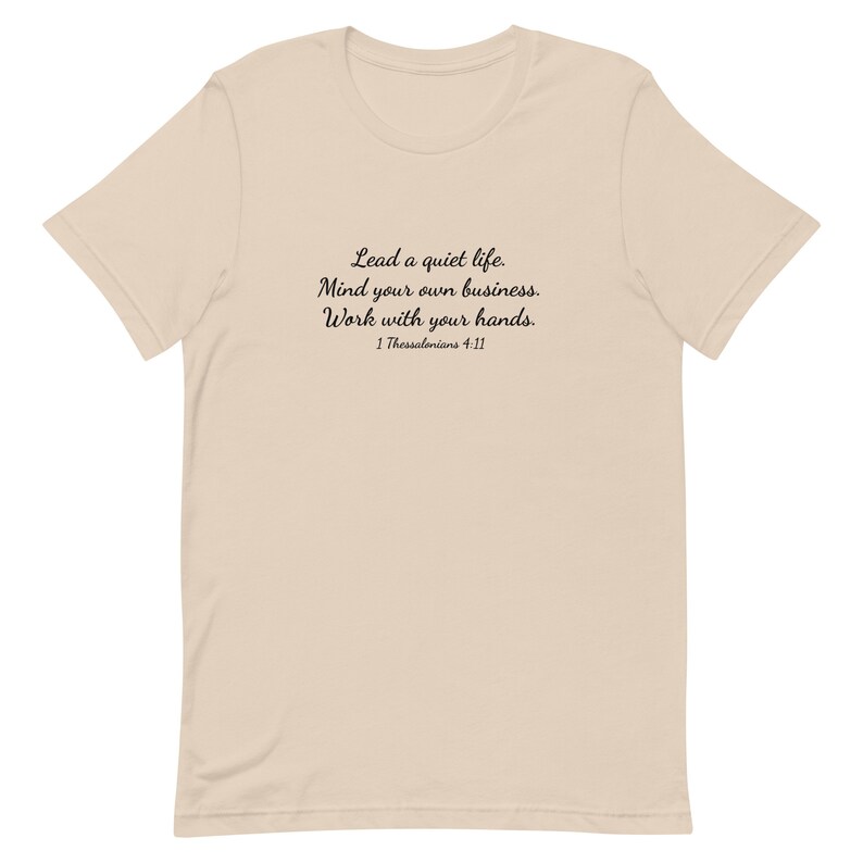 Puede incluir: Una camiseta beige con texto negro que dice "Lead a quiet life. Mind your own business. Work with your hands. 1 Thessalonians 4:11"