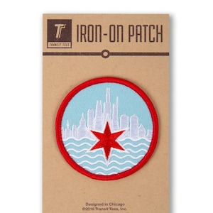 May include: Iron-on patch featuring a white silhouette of the Chicago skyline with a red star in the center, all on a light blue background with white waves at the bottom. The patch is surrounded by a red border. The text "IRON-ON PATCH" is printed on a brown card.