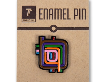 May include: Enamel pin with a colorful, geometric design in a square shape. The pin features a brown border with interior lines in purple, green, orange, pink, and blue. The pin is on a brown card with the text "ENAMEL PIN" and "TRANSIT TEES".