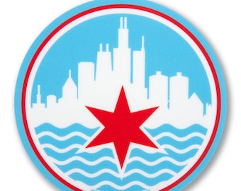 May include: A round sticker featuring the Chicago city skyline in white against a light blue background. A red six-pointed star is centered below the skyline, above wavy lines. The sticker is bordered by a red and white ring. The text "©2020 TRANSIT TEES, INC" is at the bottom.