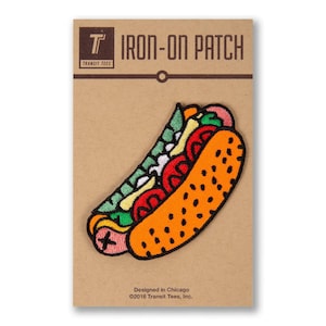 May include: Iron-on patch featuring a cartoon hot dog with mustard, ketchup, relish, and onions. The patch is on a brown card with the text "T IRON-ON PATCH TRANSIT TEES Designed in Chicago ©2016 Transit Tees, Inc."