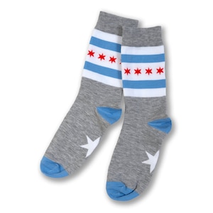 May include: A pair of gray socks with blue and white stripes and red stars. The socks have a white star on the heel.