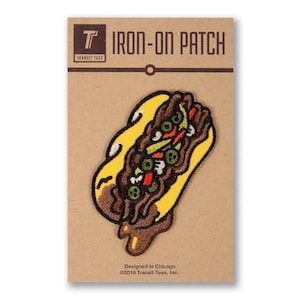 May include: Iron-on patch featuring a cartoon illustration of a Chicago Italian beef sandwich with yellow bread, brown gravy, and green peppers. The patch is on a brown card with the text "T IRON-ON PATCH TRANSIT TEES Designed in Chicago ©2016 Transit Tees, Inc."