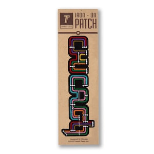 May include: Iron-on patch featuring a stylized design of the Chicago "L" train lines in various colors on a black background. The patch is packaged on a brown card with the text "IRON - ON PATCH" and "TRANSIT TEES".