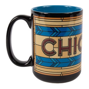 May include: Black ceramic mug with a blue interior and a black handle. The mug features a geometric design in shades of tan, blue, and orange, with the word "CHICAGO" prominently displayed in a stylized font.