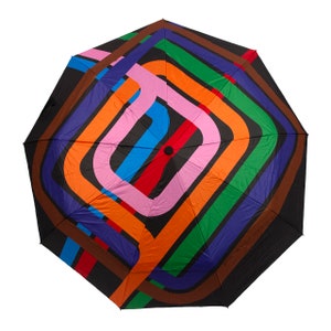 May include: A black umbrella with a colorful geometric pattern. The pattern features overlapping circles in shades of orange, green, blue, pink, and red.