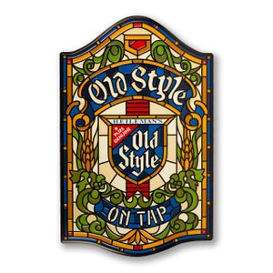 May include: A rectangular, stained-glass style sign with a black border. The sign features the words "Old Style" in a stylized font, along with the text "On Tap" and the Heileman's logo. The design incorporates blue, green, yellow, and red colors.