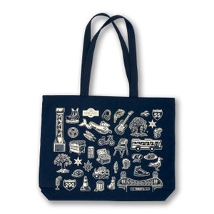 May include: A navy blue canvas tote bag with white illustrations of various icons related to the city of Minneapolis, Minnesota. The bag has two black handles and the text "The Boulevards" is printed on the front.