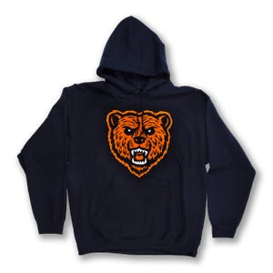 May include: A navy blue hooded sweatshirt with a large orange bear head graphic on the front.