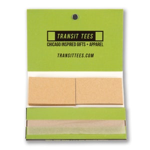 May include: A green pack of rolling papers with the text "TRANSIT TEES" and "CHICAGO INSPIRED GIFTS + APPAREL" on the front. The text "TRANSITTEES.COM" is printed on the bottom of the front of the pack.