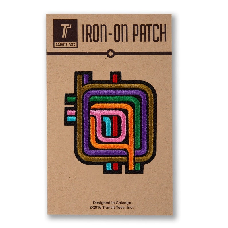 Pu&ograve; includere: Toppa da stirare con un design astratto colorato con pi&ugrave; cerchi concentrici in tonalit&agrave; di verde, arancione, viola, rosa e blu. La toppa &egrave; su una carta marrone con il testo "T IRON-ON PATCH TRANSIT TEES Designed in Chicago &copy;2016 Transit Tees, Inc."