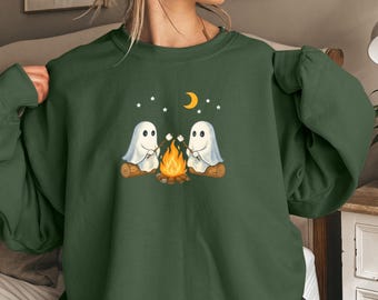 May include: A military green sweatshirt featuring a graphic of two cartoon ghosts roasting marshmallows over a campfire. The design includes a crescent moon and stars. The text "MILITARY GREEN" is at the bottom of the image.