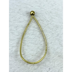 May include: A gold-toned teardrop-shaped pendant featuring a flexible, textured wire band that tapers to a point at the top, finished with a small, smooth, spherical gold-toned bead at the apex of the teardrop loop structure.