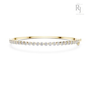 Pode incluir: Uma pulseira de ouro com uma fileira de pedras preciosas redondas e transparentes. A pulseira é exibida em um fundo branco. As pedras preciosas são uniformemente espaçadas.
