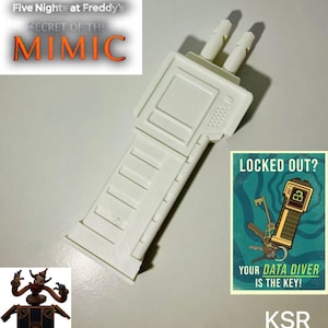 May include: A white plastic prop resembling a device, possibly a game controller or tool, with two protruding cylinders. The image includes text from "Five Nights at Freddy's: Secret of the Mimic" and a poster that says "Locked Out? Your Data Diver is the Key!"