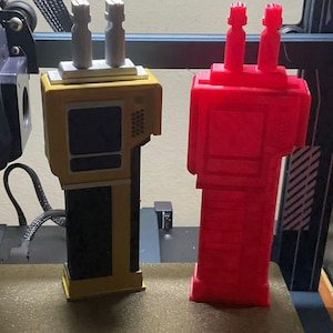 May include: Two 3D-printed models of a handheld device are displayed side-by-side. One is yellow and black, the other is red. The text "Before and after" is at the top of the image. The models have a rectangular body with two vertical antennas.