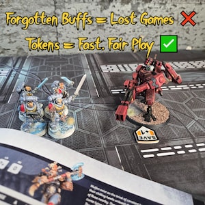 May include: Miniature tabletop game figures and tokens on a game board. The figures are painted in shades of red, gray, and yellow. Text on the board reads "Forgotten Buffs = Lost Games" and "Tokens = Fast. Fair Play."
