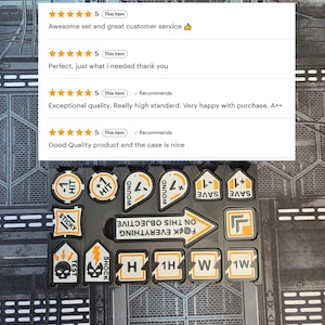 May include: A set of black and white game tokens with orange accents. The tokens include labels such as "HIT", "WOUND", "SAVE", and "STICKY". The text "F@CK EVERYTHING ON THIS OBJECTIVE" is also visible.
