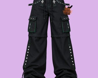 May include: Black cargo pants featuring green contrast stitching, silver-tone metal eyelets, and multiple utility pockets. The design includes adjustable straps at the waist and legs, with the text BOLD STITCH STUDIO printed near the right pocket.