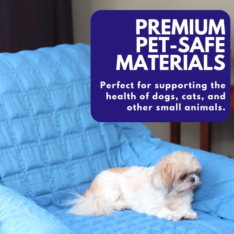 May include: A small white dog lying on a blue quilted blanket. The text "PREMIUM PET-SAFE MATERIALS" is in a blue box above the dog. The text below the box reads "Perfect for supporting the health of dogs, cats, and other small animals."