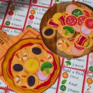 Puede incluir: Un juego para construir pizzas con ingredientes de pizza ilustrados de colores. El juego incluye una tabla de pizza de madera con una variedad de ingredientes, incluyendo pepperoni, champi&ntilde;ones, cebollas, pimientos y camarones. El juego tambi&eacute;n incluye un conjunto de cartas con diferentes recetas de pizza.
