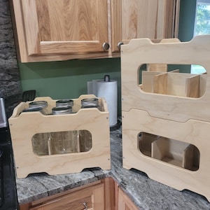 May include: Two unfinished wooden storage crates. One crate is filled with glass jars with metal lids. The other crate is stacked on top of another crate. The crates have cut-out handles and dividers.