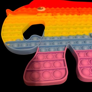 May include: A colorful elephant-shaped pop-it toy. The toy features a gradient of colors, starting with red at the top, transitioning to yellow and orange, then blue, and finally pink at the bottom. The toy has multiple bubble-like circles.