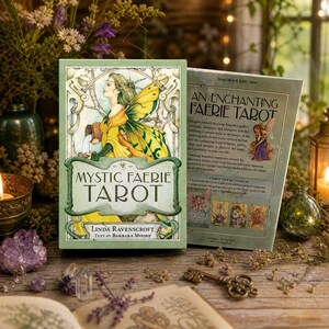 Peut inclure: Un jeu de tarot Mystic Faerie avec un design vert et doré. La boîte présente une femme avec des ailes de fée et le texte "Mystic Faerie Tarot". La boîte ouverte à côté indique "An Enchanting Faerie Tarot". Le jeu est entouré de bougies et de cristaux.