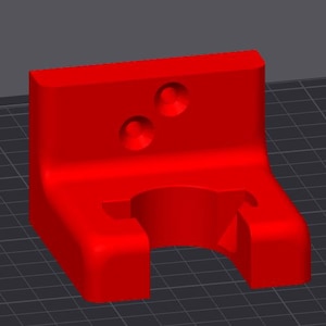 Puede incluir: Un soporte de pared de plástico rojo con dos agujeros y una abertura grande para una tubería.