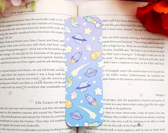May include: A blue and white bookmark with a space theme. It features a rocket, a UFO, a planet, and stars. The bookmark has the text "The Tower of Scrapple" on it.