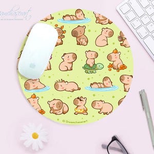 Op de afbeelding: Een ronde muismat met een lichtgroene achtergrond en een herhalend patroon van bruine capibara's in verschillende poses. De capibara's zijn omringd door kleine gele en oranje vruchten. De tekst "Dreamchaserart" staat onderaan de muismat.