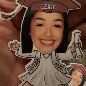 May include: A graduation cap with the name Lexie on it, a cartoon image of a person wearing a graduation gown and cap, holding a diploma, and the text "Class of 2025".