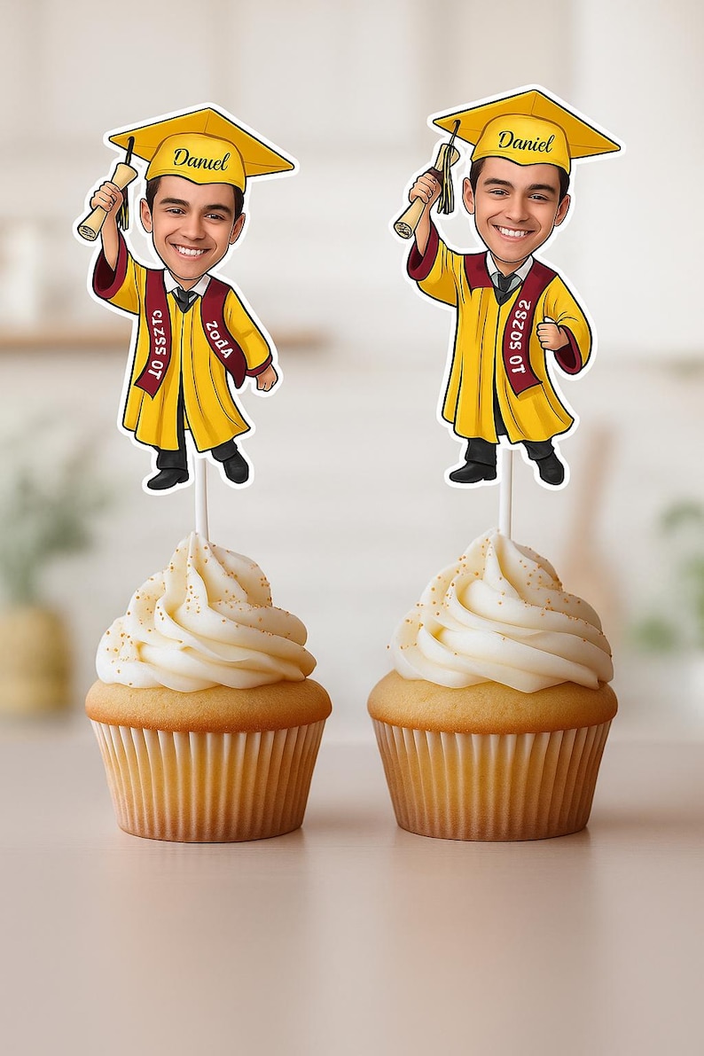 May include: Two yellow graduation cupcakes with a cartoon graduate topper. The topper is a caricature of a person wearing a graduation cap and gown, holding a diploma. The text on the topper says "Daniel" and "Class of 2023".