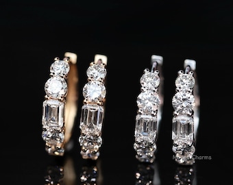 Puede incluir: Cuatro pendientes de aro de diamantes. Cada pendiente presenta una combinación de piedras preciosas claras redondas y de talla esmeralda engastadas en una banda de oro o plata. Los pendientes se muestran sobre un fondo negro.
