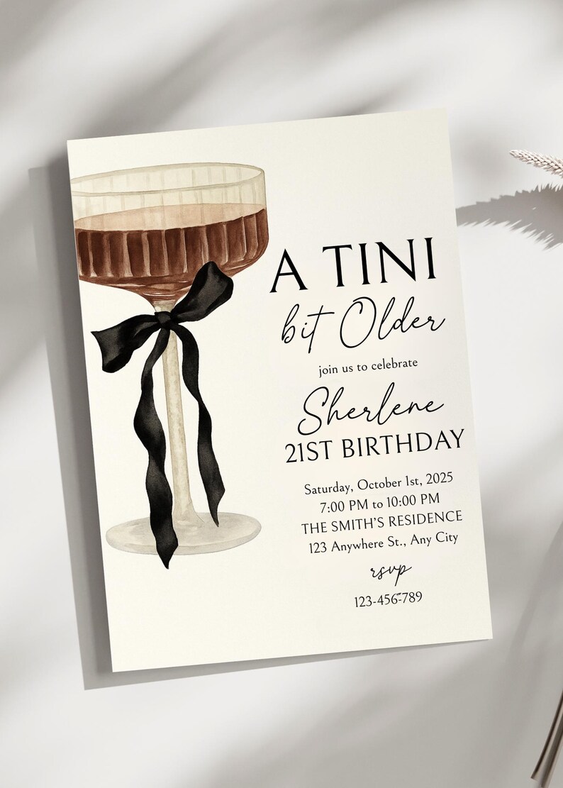 Puede incluir: Una tarjeta de invitaci&oacute;n color crema con una ilustraci&oacute;n en acuarela de una copa de c&oacute;ctel con un lazo negro. El texto dice "A Tini bit Older" y anuncia el 21 cumplea&ntilde;os de Sherlene el 1 de octubre de 2025.