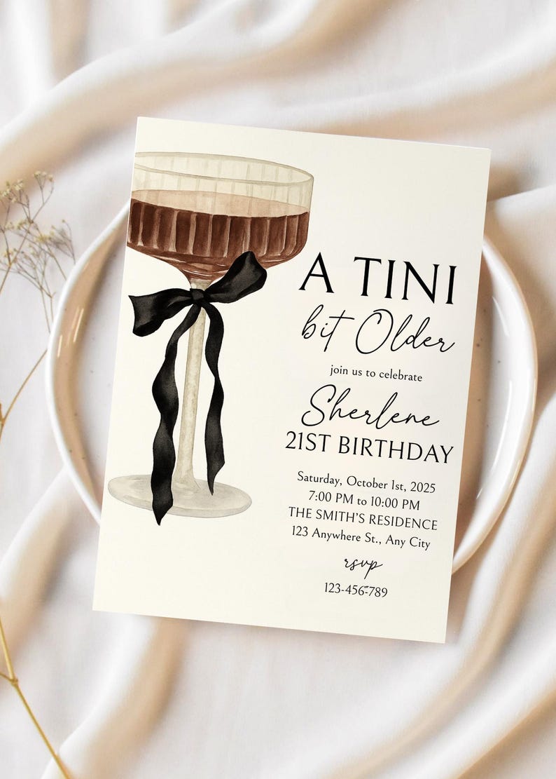 Puede incluir: Una tarjeta de invitaci&oacute;n color crema con una ilustraci&oacute;n de acuarela de una copa de c&oacute;ctel con un lazo negro. El texto dice "A TINI bit Older" y anuncia el 21 cumplea&ntilde;os de Sherlene el 1 de octubre de 2025.