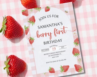Può includere: Un invito di compleanno con il testo "Unisciti a noi per il primo compleanno di Samantha". L'invito è decorato con illustrazioni di fragole e si trova su uno sfondo a quadretti rosa, circondato da fragole fresche.