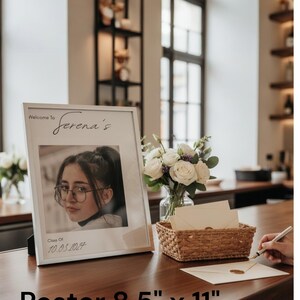 Puede incluir: Un póster enmarcado, de 21,6 cm x 27,9 cm, con una fotografía de una persona con gafas. El texto "Welcome to Serena's" está encima de la foto, con "Class Of 10.03.2024" debajo. Un ramo de rosas blancas y una cesta tejida también están sobre la mesa.