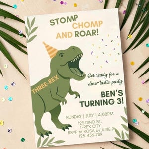 Op de afbeelding: Een rechthoekige verjaardagsuitnodigingskaart met een groene T-Rex die een geel-wit gestreepte feesthoed draagt. De tekst luidt STOMP CHOMP AND ROAR! THREE-REX, Get ready for a dino-tastic party, BEN'S TURNING 3!, SUNDAY | JULY | 4:00PM, 123 DINO ST. T-REX CITY, RSVP to ROSA by JUNE 9, 123-456-789.