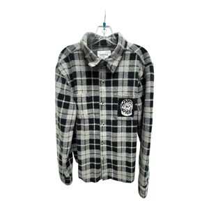 May include: A black and gray plaid flannel shirt with a button-down front and a collared neckline. The shirt features a patch on the chest that reads "WAR PIGS". The shirt is hanging on a hanger.